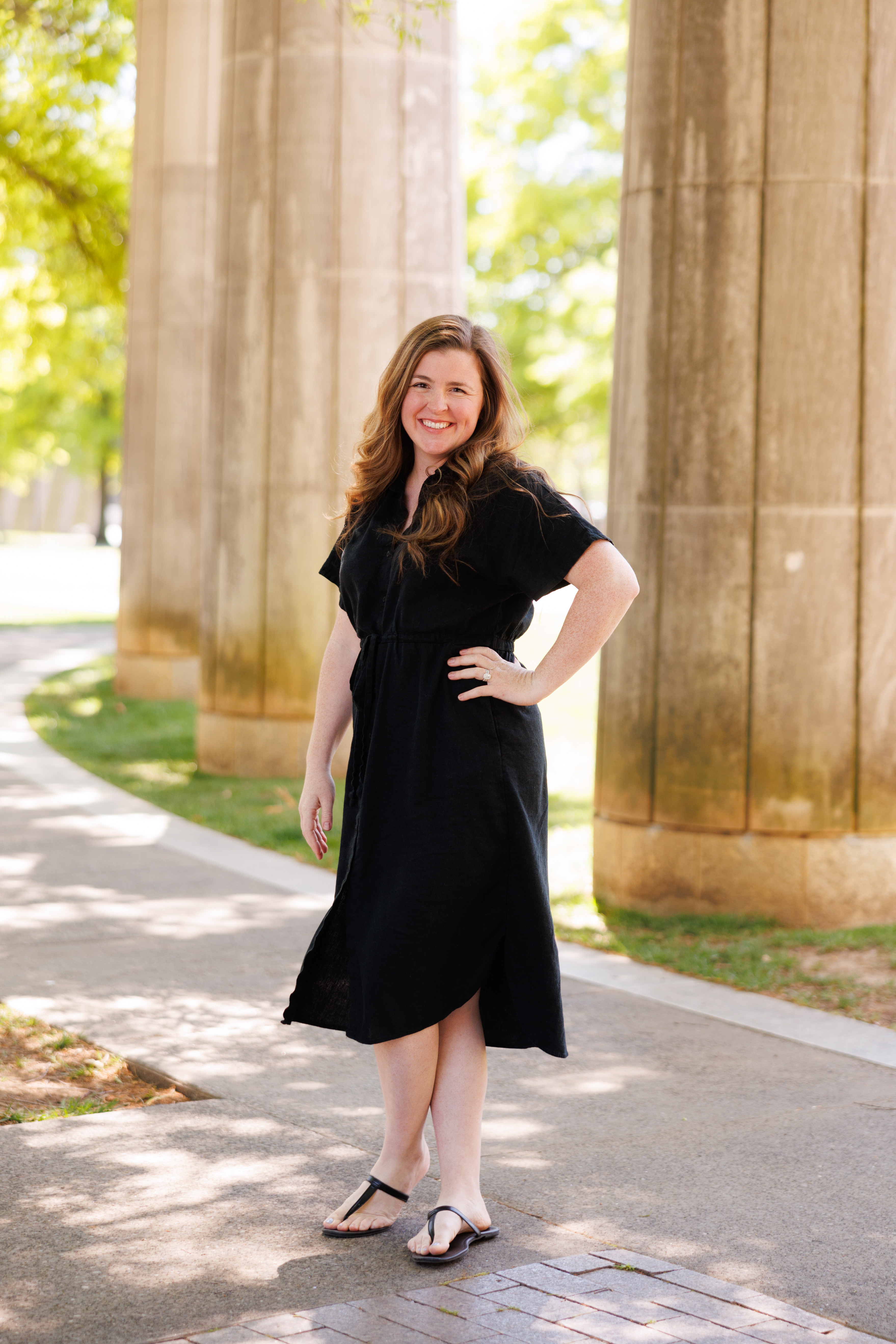 Outdoor, vertical shot of Caverly Warren standing and smiling at the camera